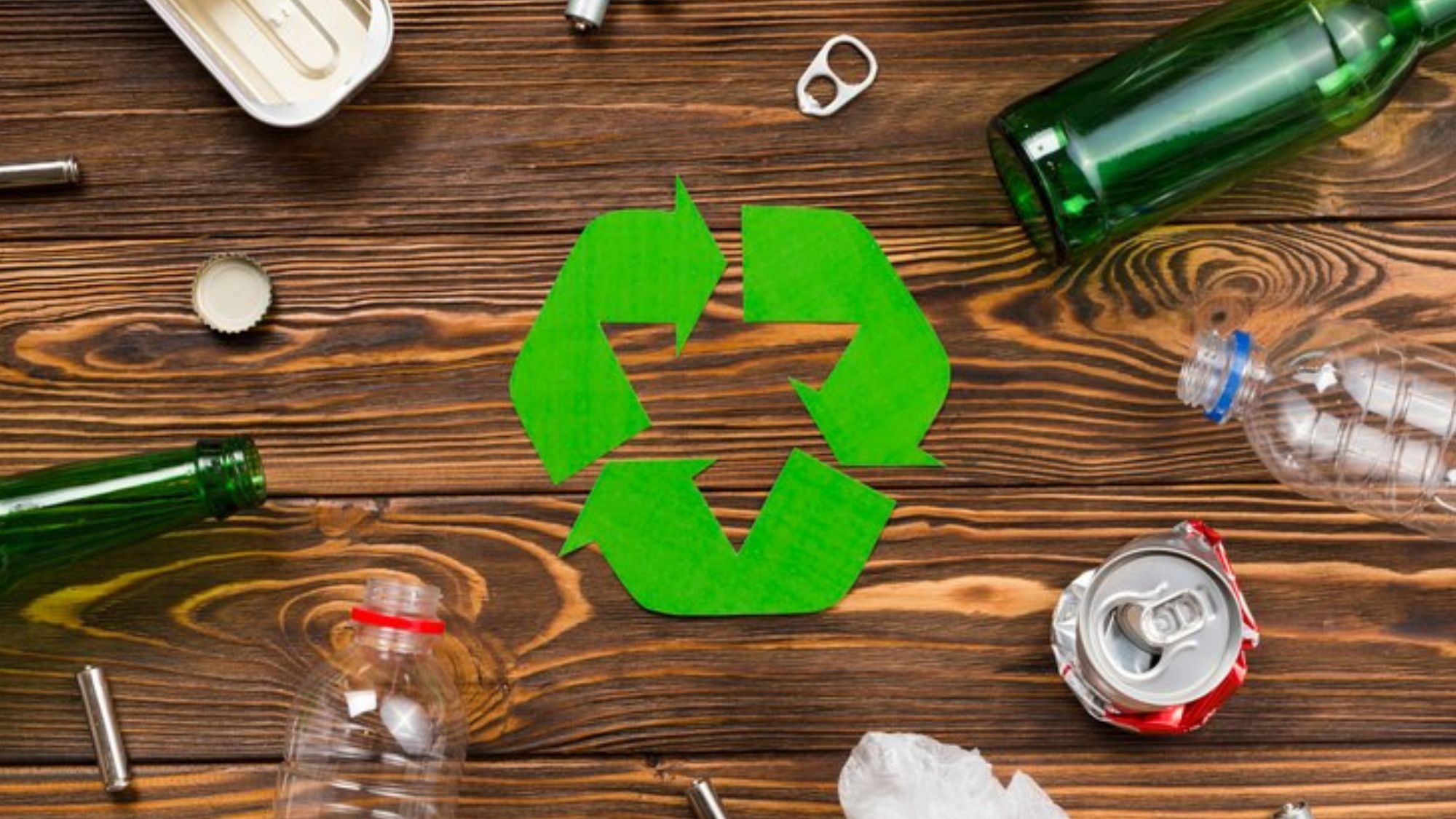 Recycling symbol on wooden table with bottles and other items